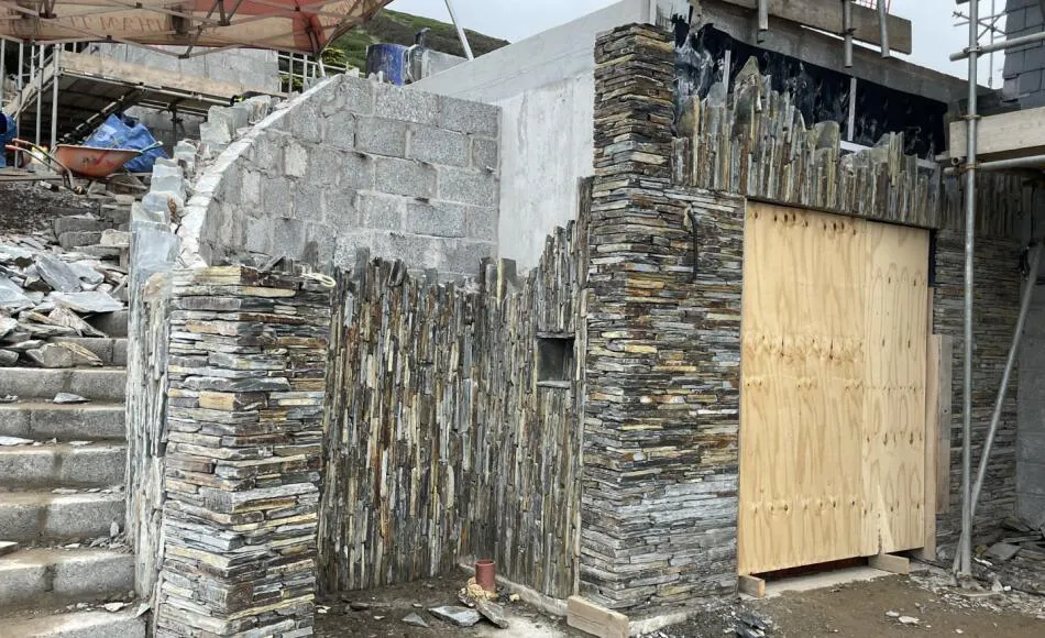 Stonework cladding around the below ground storage area, with stair curving around external shower into the landscape	