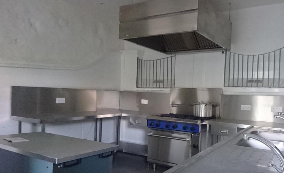 Commercial grade kitchen facilities integrated into existing space, retaining traditional agricultural features such as stall paneling and metal stall guards.