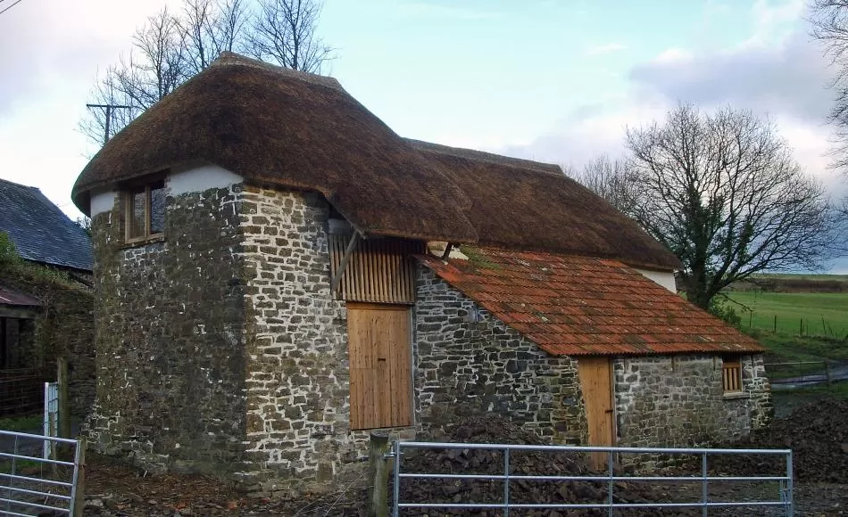 After repairs - re-thatched and clay tiled, masonry repairs and new windows and doors.