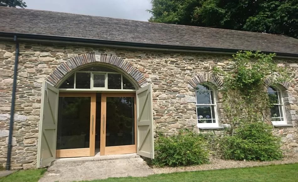 Entrance to the converted barn with new inner sliding glazed doors for additional daylight and retained originally boarded hinged doors
