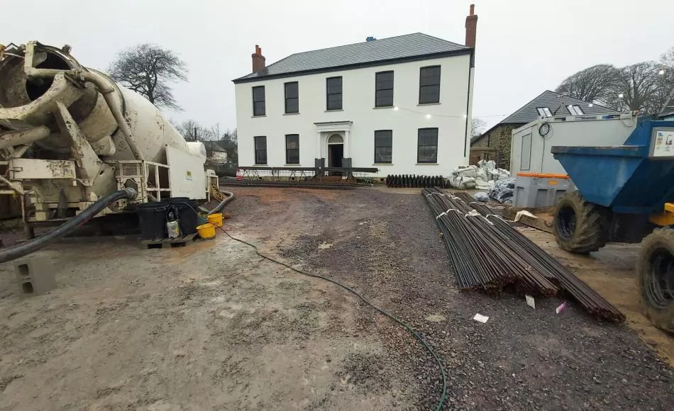 Concrete mixer and reinforcing bars in front of the listed Manor house
