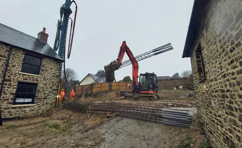 Excavator lifting reinforcing bars up ready to drive them into the wet concrete pile