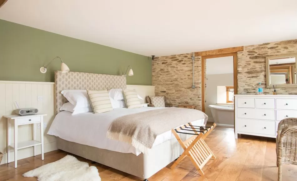 The linhay conversion bedroom and bathroom with exposed stone and historic lintels